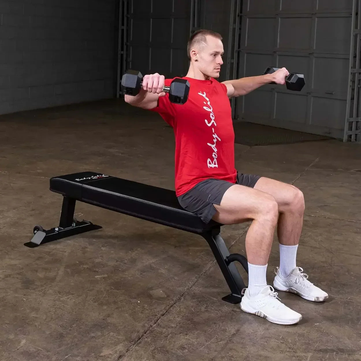 Mann trainiert mit Hanteln auf Hantelbank im Fitnessstudio