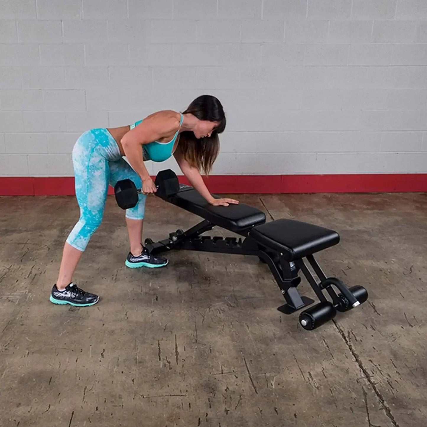 Frau trainiert mit Hanteln an Hantelbank im Fitnessstudio – ideales Homegym Equipment für Krafttraining