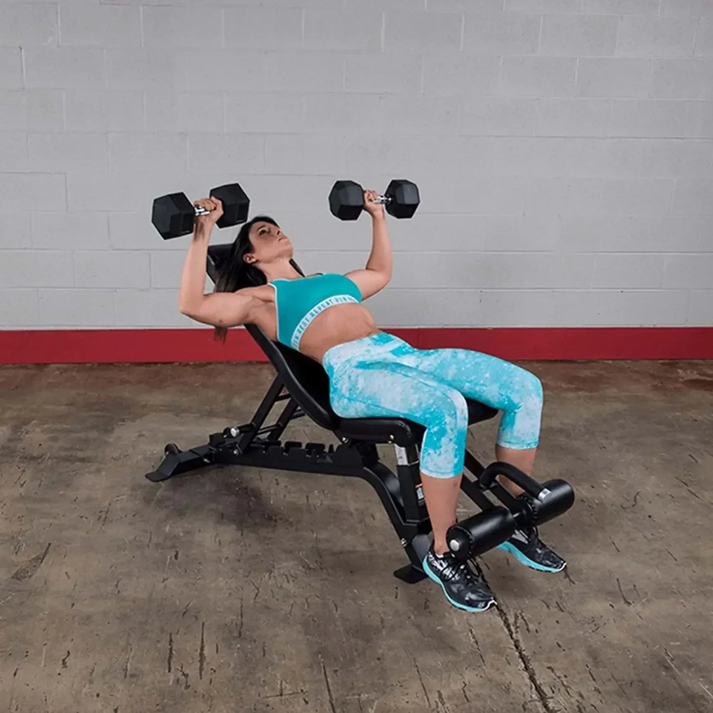 Frau trainiert mit Hanteln auf Hantelbank im Fitnessstudio – Krafttraining für Homegym & Studio
