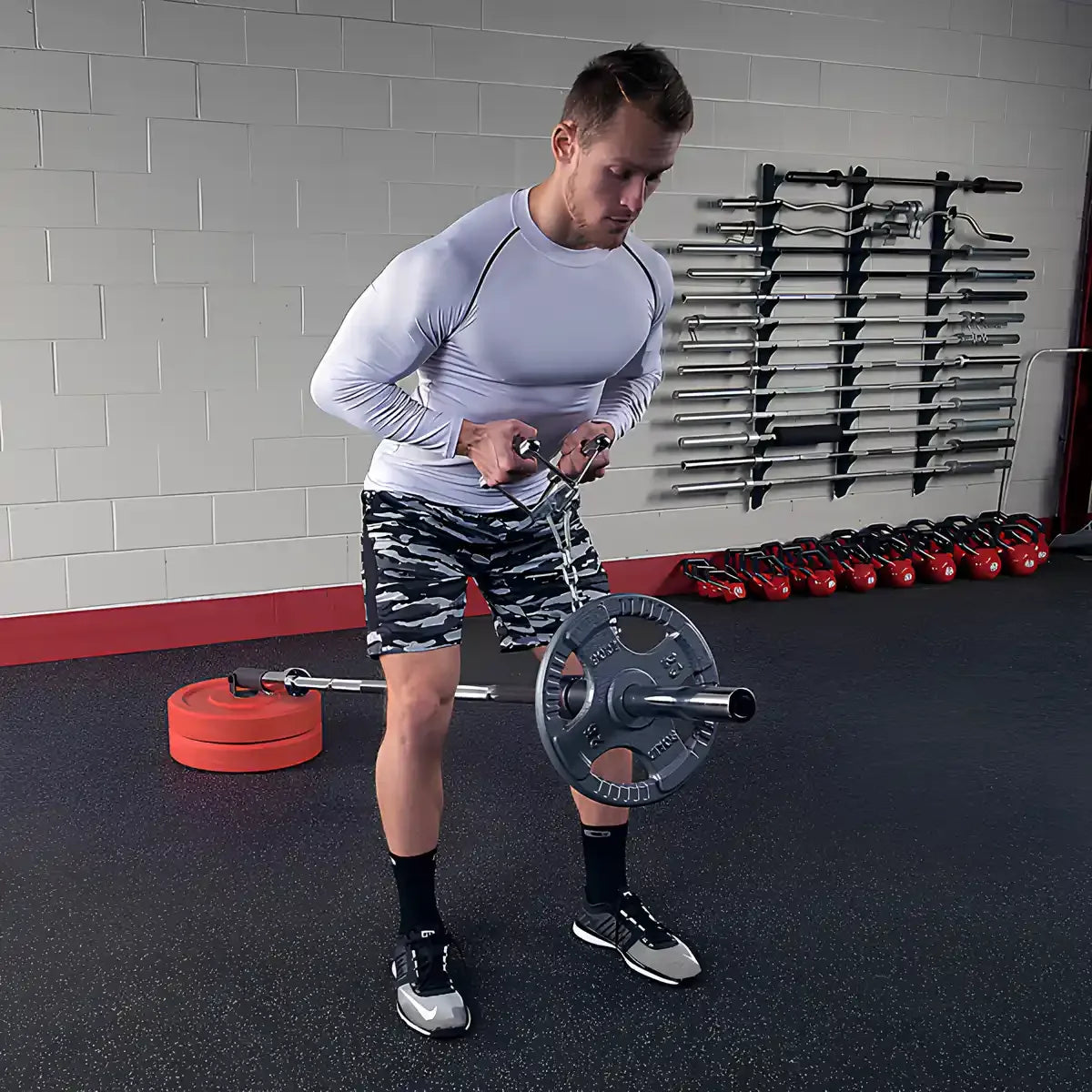 Mann trainiert mit Hantel und Ketten im Fitnessstudio – Kraftsport Equipment für Homegym & Studio